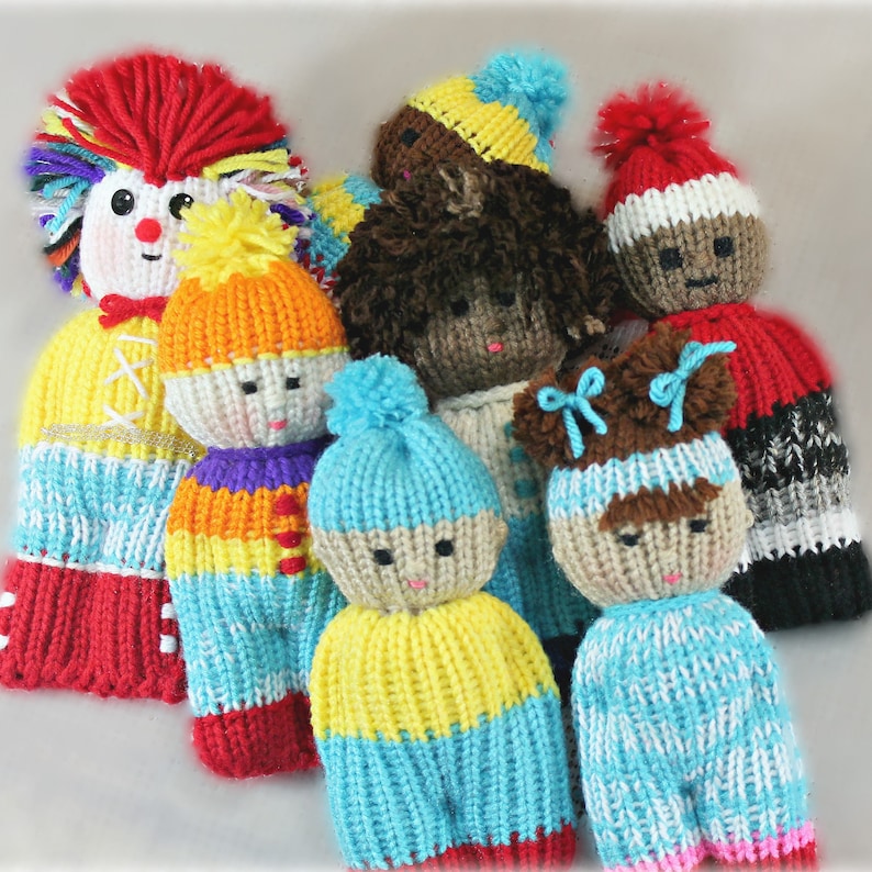 May include: A group of seven knitted dolls with different colored yarn and facial features. The dolls are wearing various hats and clothing, including a red and white striped hat, a blue and yellow hat, and a red and white striped dress.