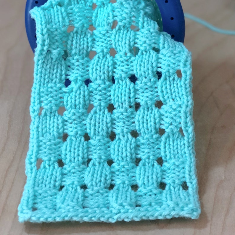 May include: A turquoise knitted fabric with a textured pattern of small squares and circles.