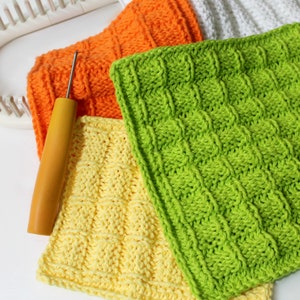Peut inclure: Plusieurs carr&eacute;s tricot&eacute;s &agrave; la main aux couleurs vives : orange, jaune et vert. Un crochet &agrave; manche en bois repose sur les carr&eacute;s, avec un m&eacute;tier &agrave; tisser blanc en arri&egrave;re-plan. Les carr&eacute;s pr&eacute;sentent un motif textur&eacute; et tiss&eacute;.