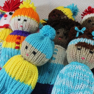 May include: A group of knitted dolls with different colored yarn and facial features. The dolls are wearing hats and some have bows.