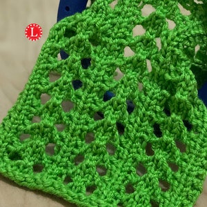 May include: A close-up of a green crocheted fabric with a repeating pattern of open squares. The fabric is soft and textured.