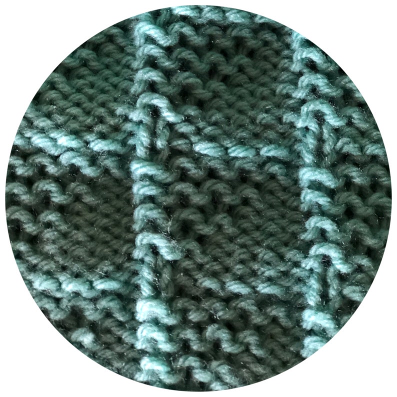 May include: Close-up of a knitted fabric with a textured, grid-like pattern. The yarn is a blend of teal and dark teal, creating a subtle color gradient. The stitches are clearly defined, showcasing the craftsmanship of the knit.