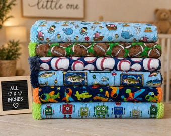May include: A stack of seven plush blankets with various patterns, including footballs, baseballs, fish, robots, and airplanes. Each blanket measures 17 x 17 inches.
