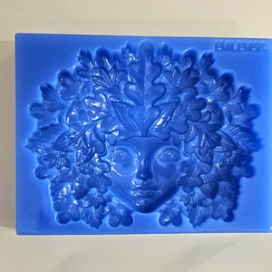 May include: Blue silicone mold with a detailed design of a woman's face surrounded by leaves and acorns. The mold is labeled "EMLEM3C".