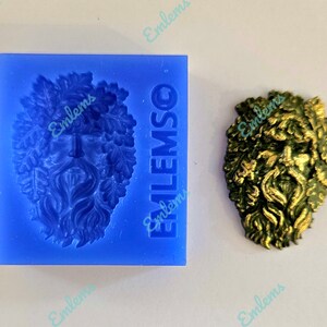 Peut inclure: Un moule en silicone bleu avec le texte "EMLEMSO" sur le côté. Le moule est en forme de visage d'homme vert avec des feuilles et des vignes. Une coulée en résine dorée de l'homme vert est présentée à côté du moule.