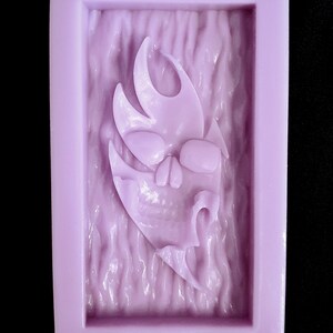 May include: Purple silicone mold with a detailed design of a skull with flames. The mold is rectangular and has the word "EMLEPSO" printed on the bottom.