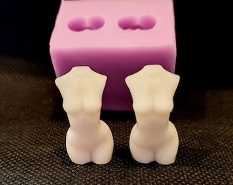 May include: Two white silicone molds for making resin crafts. The molds are shaped like the upper torso of a person. The molds are sitting on a black textured surface.