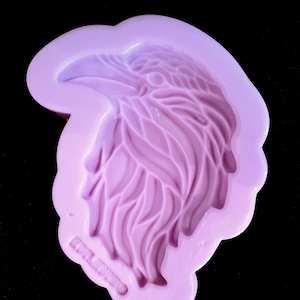 May include: Purple silicone mould of an eagle head with detailed feathers. The mould is designed for creating resin crafts.
