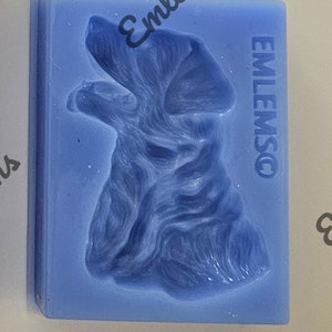 May include: Blue silicone mold for making a dog shaped cake or other edible treat. The mold has the word "EMLEMSO" embossed on the side.