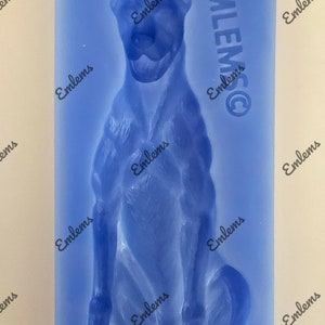 May include: Blue silicone mould of a sitting dog. The mould is for making cake pops or other edible treats. The mould has the word "Emlems" printed on it.