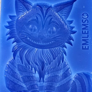 May include: Blue silicone mould of a Cheshire Cat from Alice in Wonderland. The mould is detailed with a striped pattern and a mischievous grin.