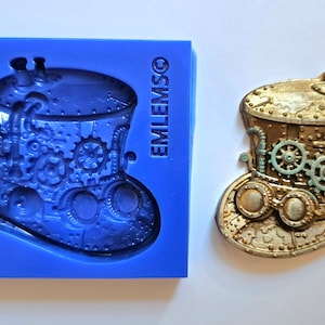 Op de afbeelding: Een blauwe siliconen mal voor het maken van een steampunk-hoed met tandwielen, pijpen en een bril. De mal is gemarkeerd met "EMLEMSO".
