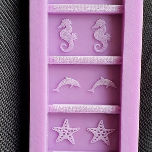 May include: Purple silicone mold with six different sea creature designs. The mold features two sea turtles, two seahorses, two dolphins, two starfish, and two seashells.