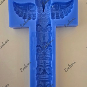 May include: Blue silicone mold for making a totem pole with an owl at the top. The mold is shaped like a cross with the totem pole in the center. The mold is labeled "EMLEMSCO".