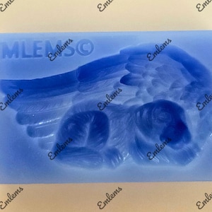 Op de afbeelding: Blauwe siliconen mal met de tekst "EMLEMSO" en een reliëf ontwerp van een engelenvleugel met een slapende baby erin.