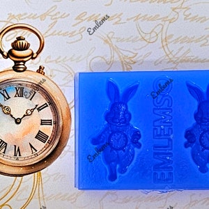 May include: Blue silicone mould with two rabbit-shaped cavities. Each rabbit is holding a pocket watch. The mould is labelled "EMLEMS" on the side.