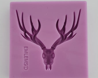 May include: Purple silicone mold for making a deer skull with antlers. The mold has the text "EMLEMS®" on the bottom.