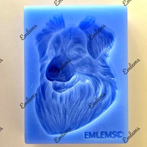 Peut inclure: Moule en silicone bleu pour faire un gâteau ou une autre friandise comestible en forme de tête de chien. Le moule présente un design détaillé d'un visage de chien avec de la fourrure et une expression joyeuse. Le moule est étiqueté "EMLEMSCO".