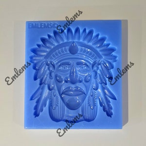 May include: Blue silicone mould of a Native American man's face with a headdress. The mould is square and has the word "Emblems" printed on it.