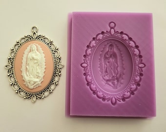 May include: A silicone mold for making a pendant featuring a religious image of the Virgin Mary in a silver frame. The mold is purple and the image is in a white oval.