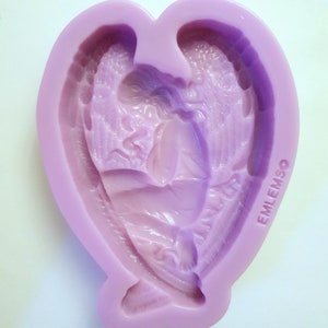 May include: A purple silicone mold shaped like a heart with an angel design inside. The mold has the word "EMLEMSO" printed on the side.