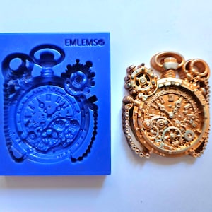 Könnte beinhalten: Eine goldfarbene, detaillierte Steampunk-Taschenuhr mit Zahnrädern und einer Kette. Die Uhr befindet sich neben einer blauen Silikonform der gleichen Uhr.
