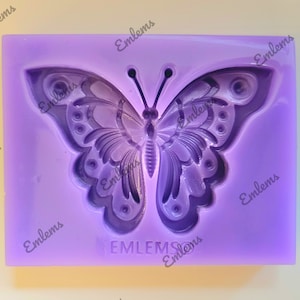 Może przedstawiać: Fioletowa forma silikonowa z detalicznym wzorem motyla. Forma służy do tworzenia przedmiotów dekoracyjnych, takich jak mydło, świece lub żywica.