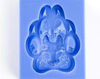 May include: A blue silicone mould shaped like a wolf paw print. The mould is designed to create a detailed replica of a wolf's paw.