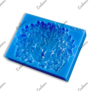 May include: Blue silicone mold with a detailed design of a tree with leaves and a bird inside. The mold is for making decorative items like cake toppers or soap.