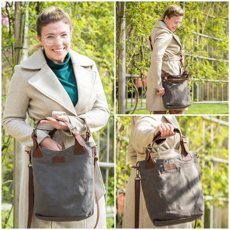 May include: A gray canvas tote bag with brown leather accents and a long shoulder strap. The bag is shown being held by a person wearing a beige coat.