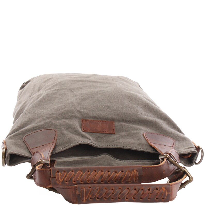 May include: A gray canvas tote bag with brown leather straps and braided handles. The bag has a brown leather patch with the word "Linen" on it.
