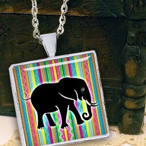 May include: A silver necklace with a square pendant featuring a black silhouette of an elephant on a colorful striped background.