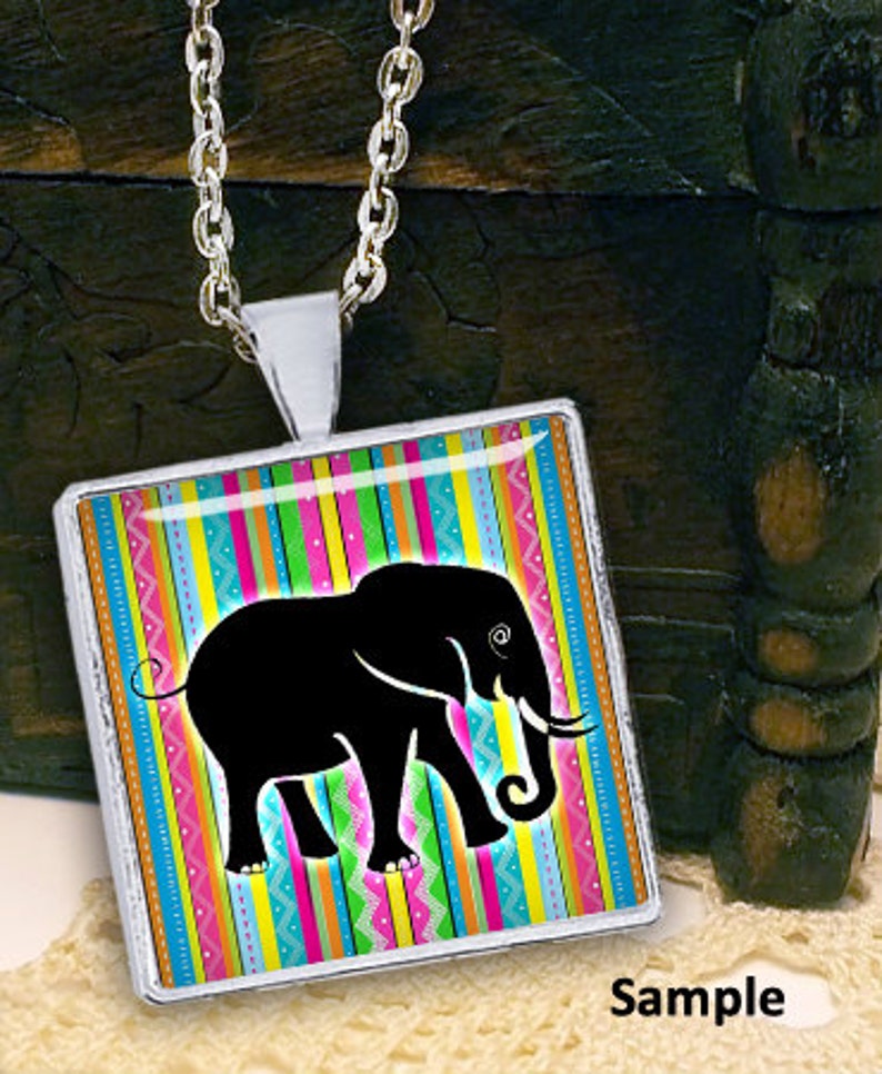 May include: A silver necklace with a square pendant featuring a black silhouette of an elephant on a colorful striped background.