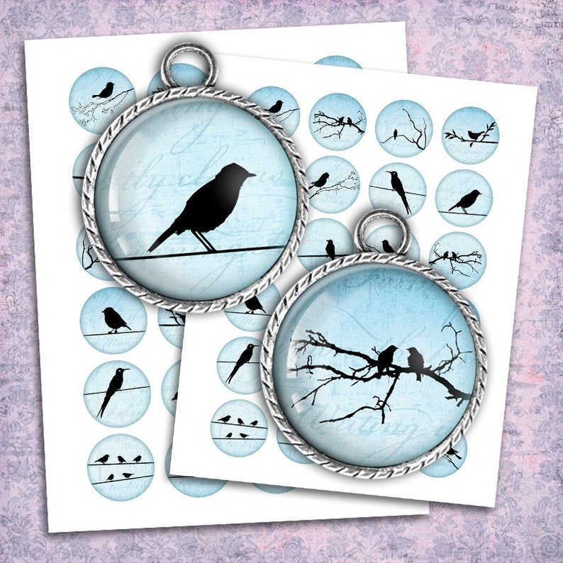 May include: Two silver charm pendants with blue glass inserts. One pendant features a single black bird silhouette on a wire, the other features three black birds on a branch. Both pendants have a distressed, vintage look.