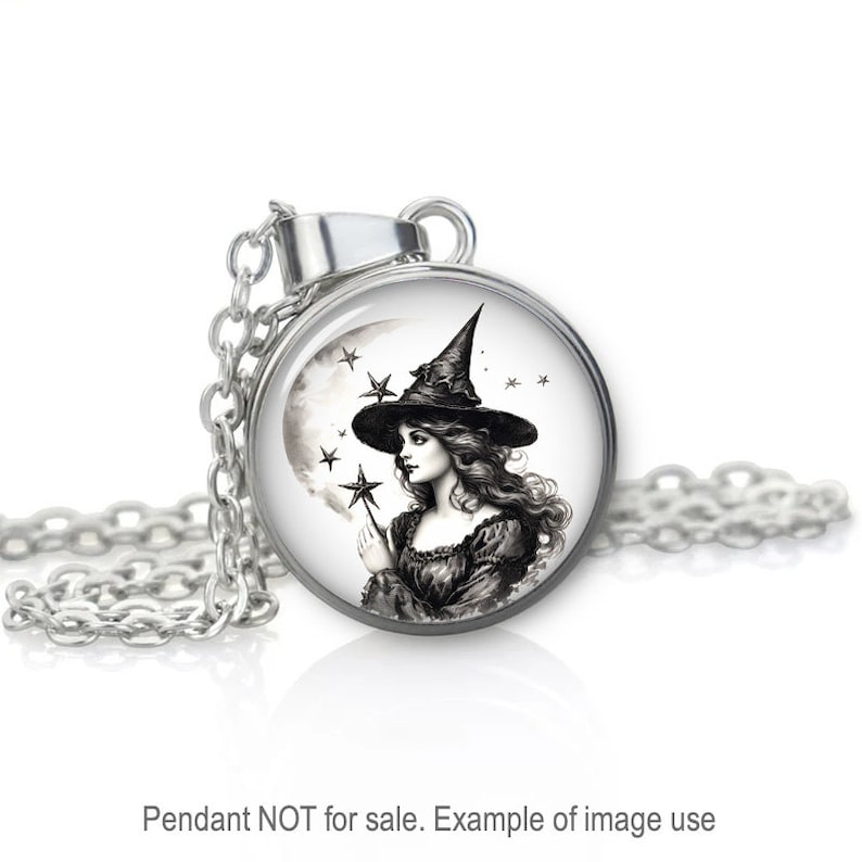 May include: A silver necklace with a round glass pendant featuring a black and white illustration of a witch with a pointed hat, holding a wand in front of a crescent moon and stars.