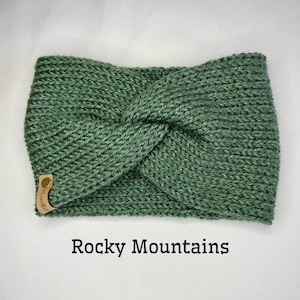 May include: A green knitted headband with a knotted design. The headband has a small leather tag with the text "Rocky Mountains" on it.