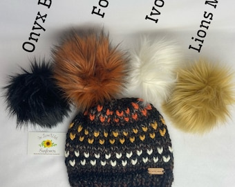 May include: A black, brown, and white knit beanie with a pom pom. Choose your pom from the options: Onyx Black, Foxy, Ivory, or Lions Mane.