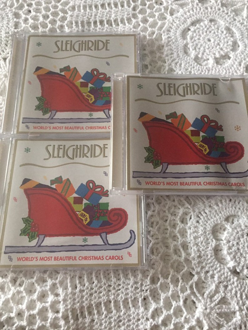 May include: Three CD cases with a red sleigh filled with presents and the text "Sleighride" and "World's Most Beautiful Christmas Carols" on the front.