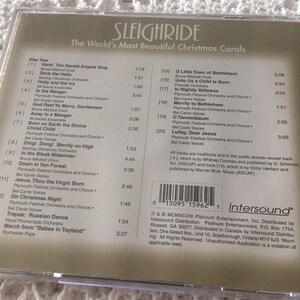 May include: The back of a CD case for a Christmas music compilation titled "Sleighride: The World's Most Beautiful Christmas Carols". The case features a list of songs and artists, including "Hark! The Herald Angels Sing" by Bruce Mitchell Choir, "Deck the Halls" by Barclay Christmas Orchestra, and "O Little Town of Bethlehem" by Bruce Mitchell Choir. The case also includes a barcode and copyright information.
