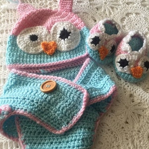 May include: A crocheted baby outfit set in pink and blue with an owl design. The set includes a hat, booties, and a diaper cover.