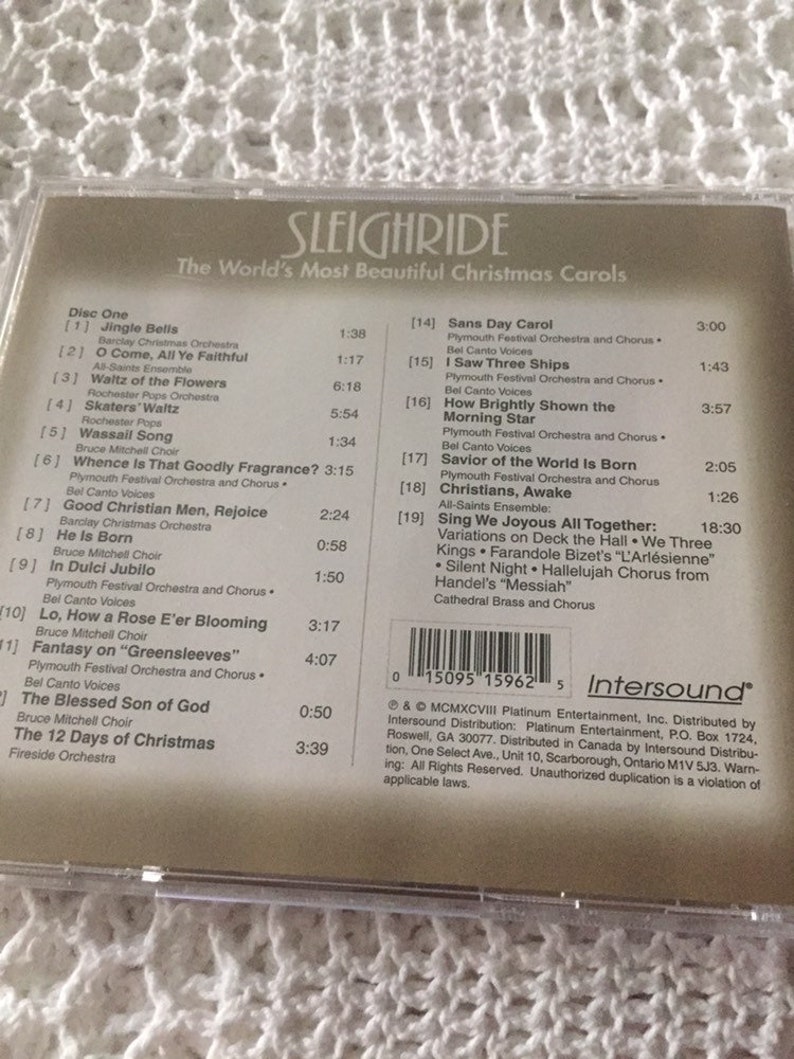 May include: A CD case with a beige background and a white label. The label has the title "Sleighride: The World's Most Beautiful Christmas Carols" and a list of Christmas songs with their corresponding track numbers and artists. The CD case also has a barcode and the Intersound logo.