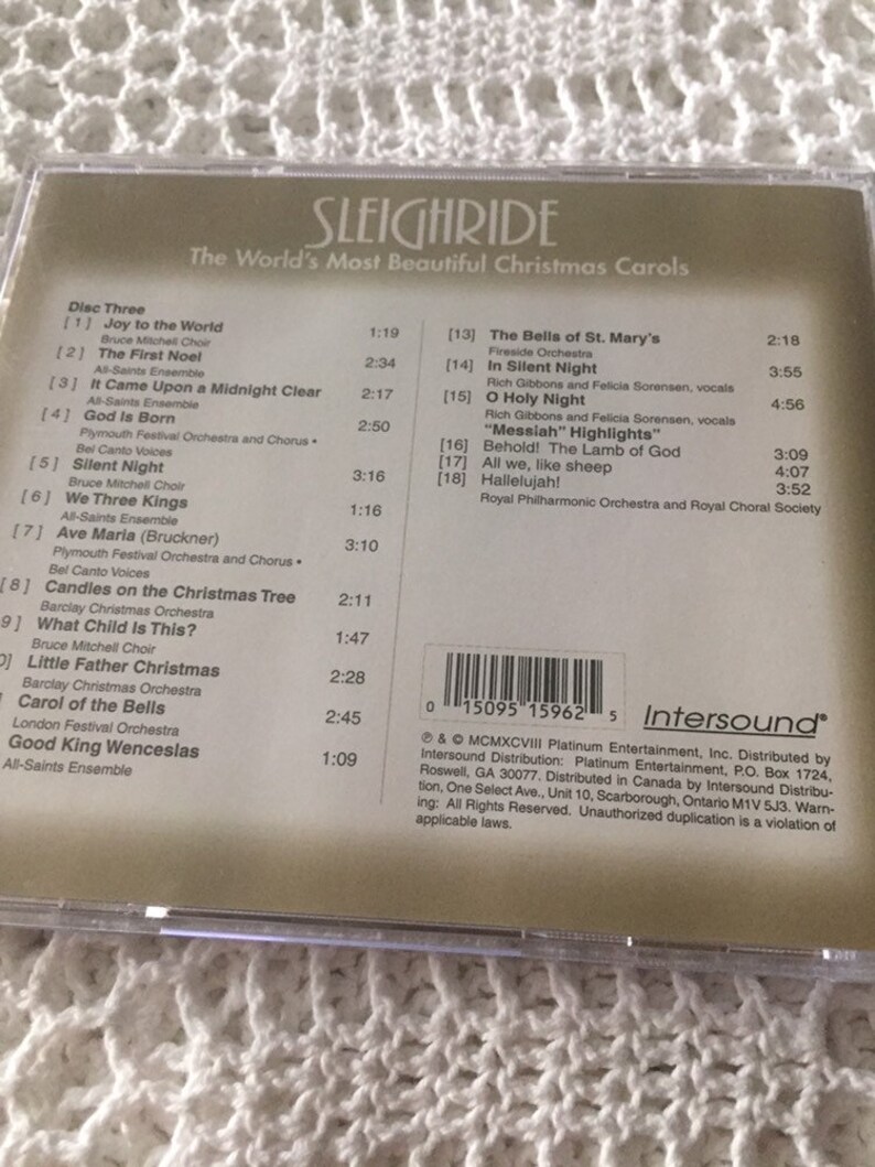 May include: A CD case with a gold background and the title "Sleighride: The World's Most Beautiful Christmas Carols". The back of the case lists the songs on the CD, including "Joy to the World", "The First Noel", "It Came Upon a Midnight Clear", "God Is Born", "Silent Night", "We Three Kings", "Ave Maria", "Candles on the Christmas Tree", "What Child Is This?", "Little Father Christmas", "Carol of the Bells", and "Good King Wenceslas".