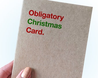 Pode incluir: Um cartão castanho com o texto "Obligatory Christmas Card." impresso em vermelho e verde.