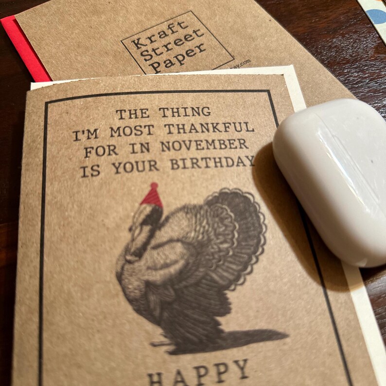 May include: A brown card with a turkey wearing a red Santa hat. The card says "The thing I'm most thankful for in November is your birthday." and "Happy".