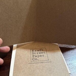 May include: A folded card with a brown paper exterior. The back of the card has a logo that reads "Kraft Street Paper Co." and the website address "www.kraftstreetpaperco.etsy.com". The bottom of the card reads "Printed on 100% Recycled Paper".