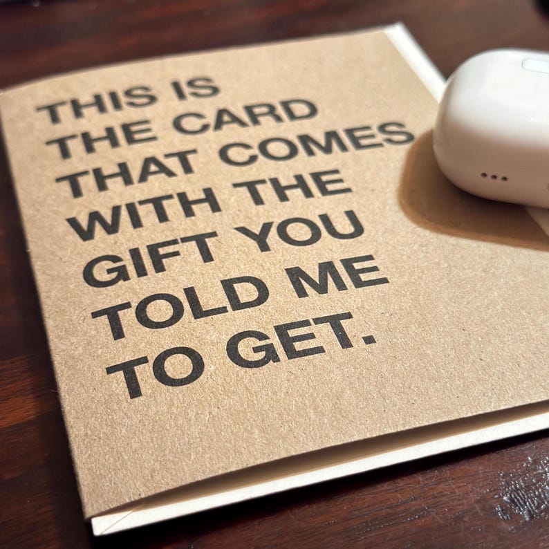 Może przedstawiać: Brązowa karta z białym tekstem, kt&oacute;ry brzmi "THIS IS THE CARD THAT COMES WITH THE GIFT YOU TOLD ME TO GET."