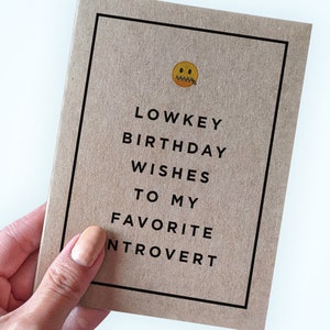 May include: A brown card with a black border and the text "Lowkey Birthday Wishes To My Favourite Introvert" with a yellow emoji of a face with a zipper over the mouth.