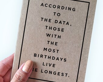 May include: A brown card with black text that reads "According to the data, those with the most birthdays live the longest."