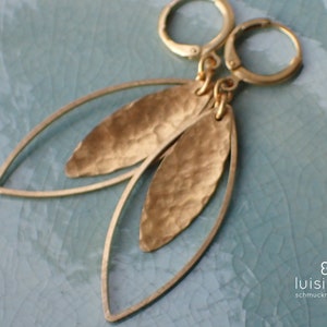 Puede incluir: Pendientes de hoja de oro con textura martillada. Los pendientes tienen forma de lágrima y tienen un bucle de alambre para colgar.