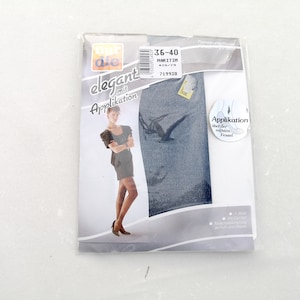 Könnte beinhalten: Packung mit blickdichten blauen Strumpfhosen mit einer Applikation am rechten Knöchel. Die Verpackung zeigt eine Frau in einem schwarzen Kleid und Strumpfhosen. Die Packung enthält außerdem den Text "elegant mit Applikation" und "36-40 MARITIM".